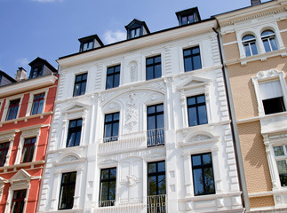 Eine Reihe mehrstöckiger Gebäude mit reich verzierten Fassaden, großen Fenstern und dekorativen architektonischen Elementen schimmerten unter dem klaren blauen Himmel, ähnlich wie eine Szene aus einem Gemälde von Maler Lauer. - Lauer maler & raumdesign - Bodenbeläge, Vinylboden, Farben, Sonnenschutz, Malerarbeiten - Bahnhofstr. 5a - 36280 Oberaula